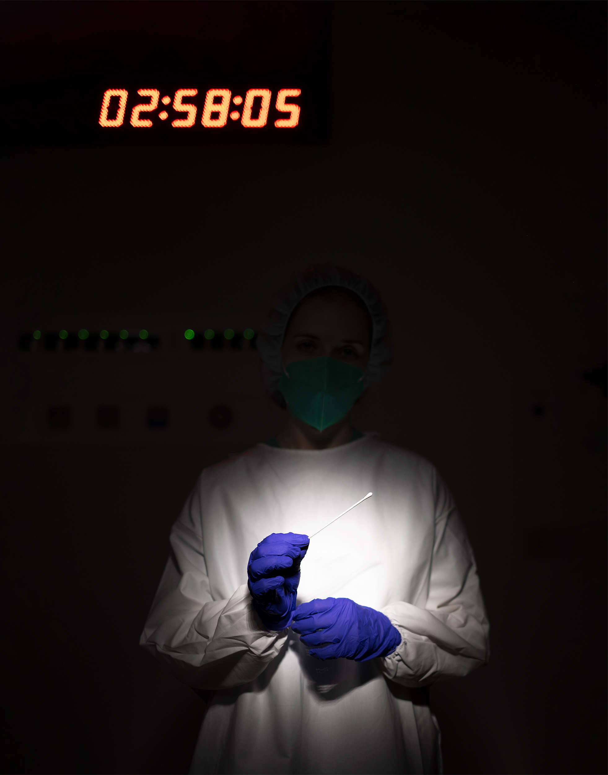 Enfermeira em ambiente escuro com equipamento de proteção individual segura zaragatoa com luvas.