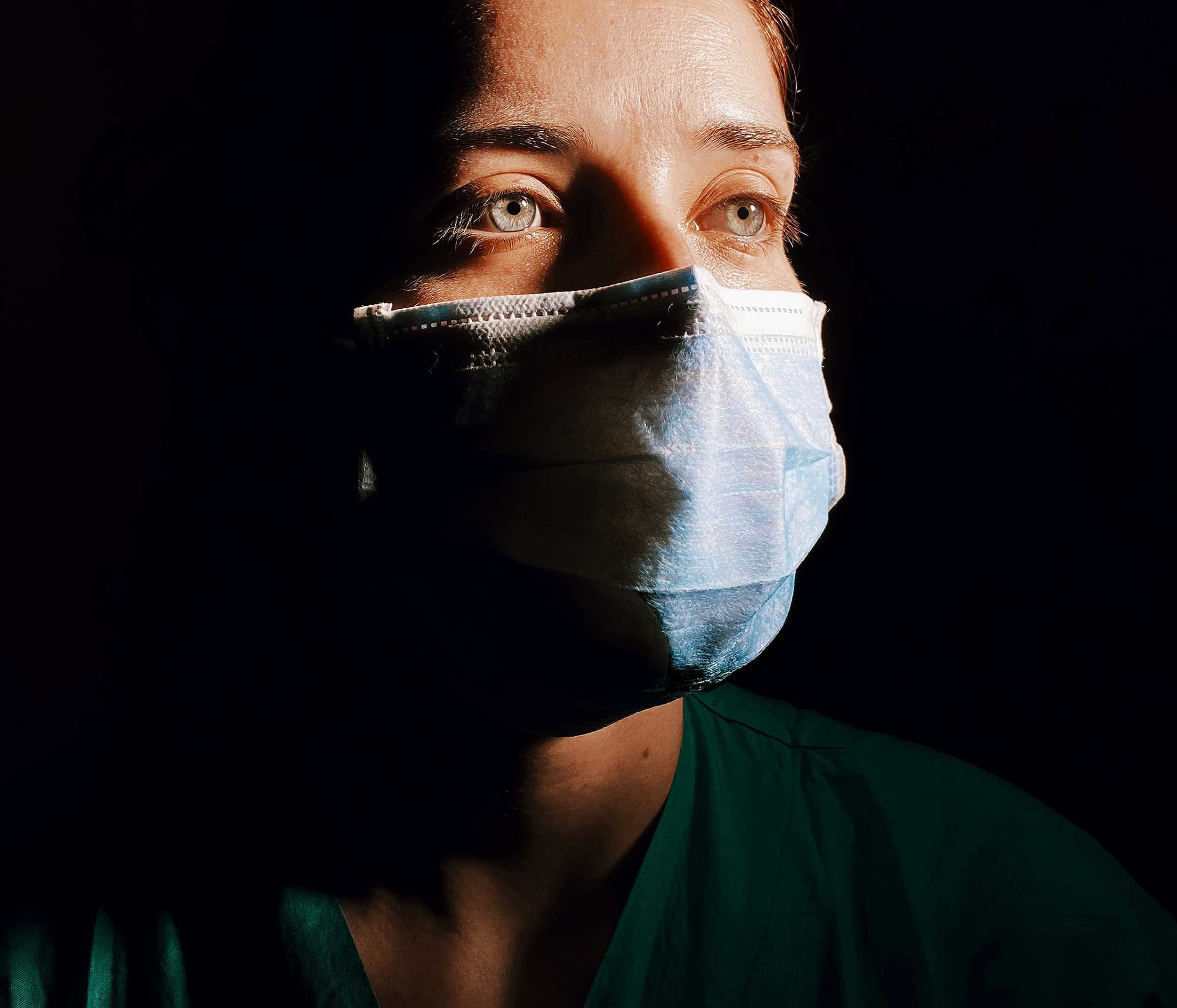 Retrato a enfermeira com olhos azuis usando máscara cirúrgica azul.