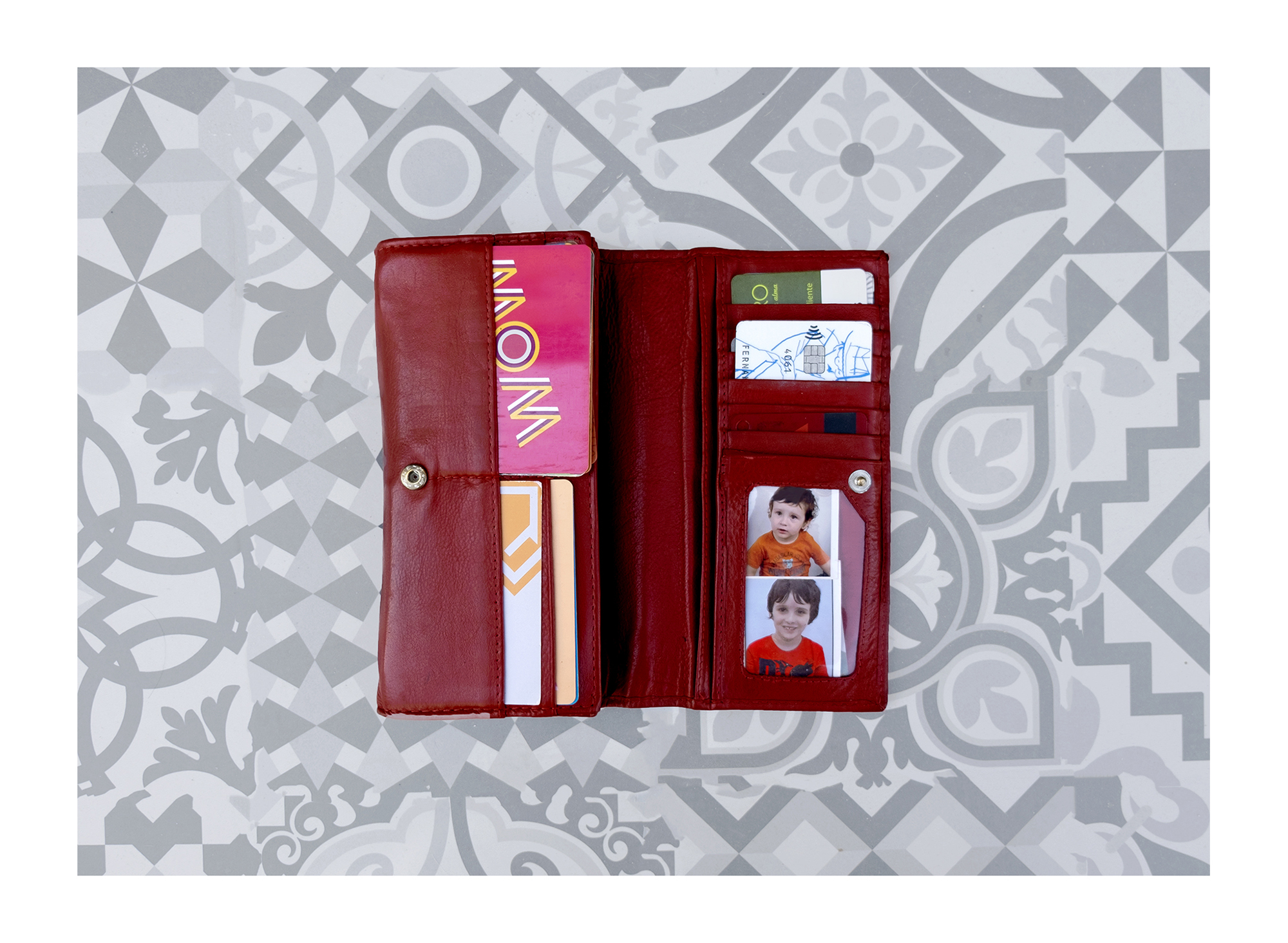 Carteira preta com várias fotografias tipo passe e figuras religiosas.