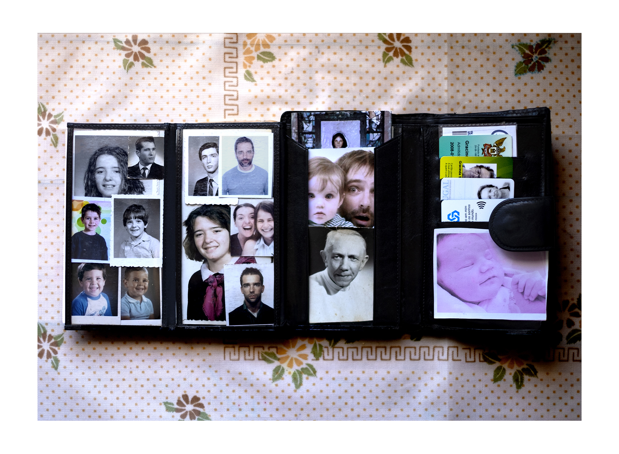 Carteira preta com três fotografias e cartões bancários coloridos.