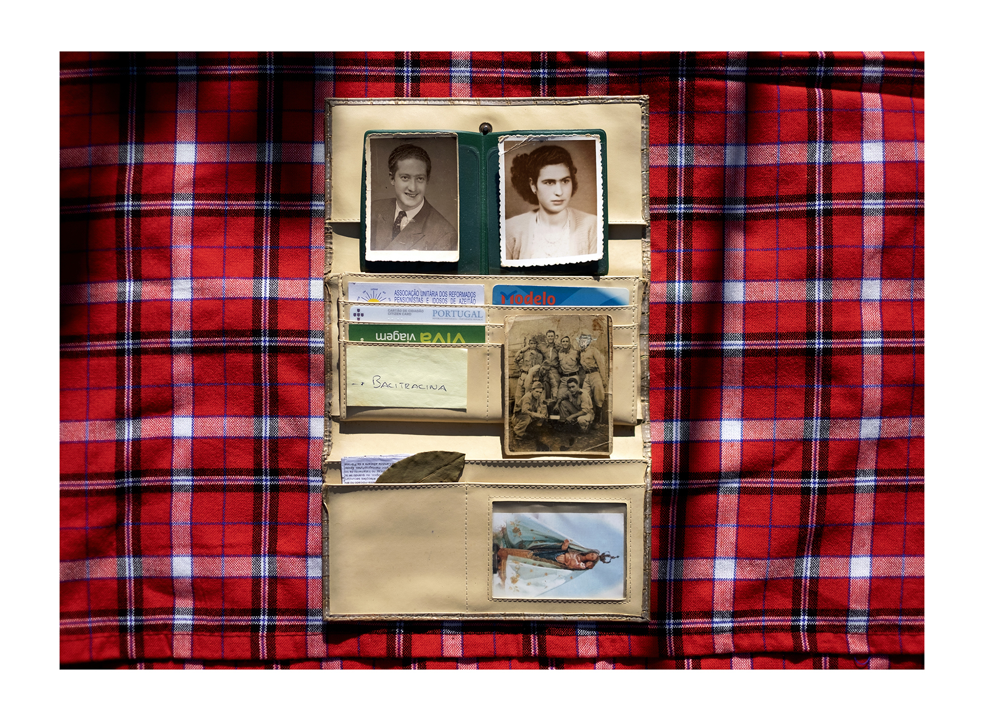 Carteira com fotografias de homem, mulher e grupo de militares em fundo padrão tartan.