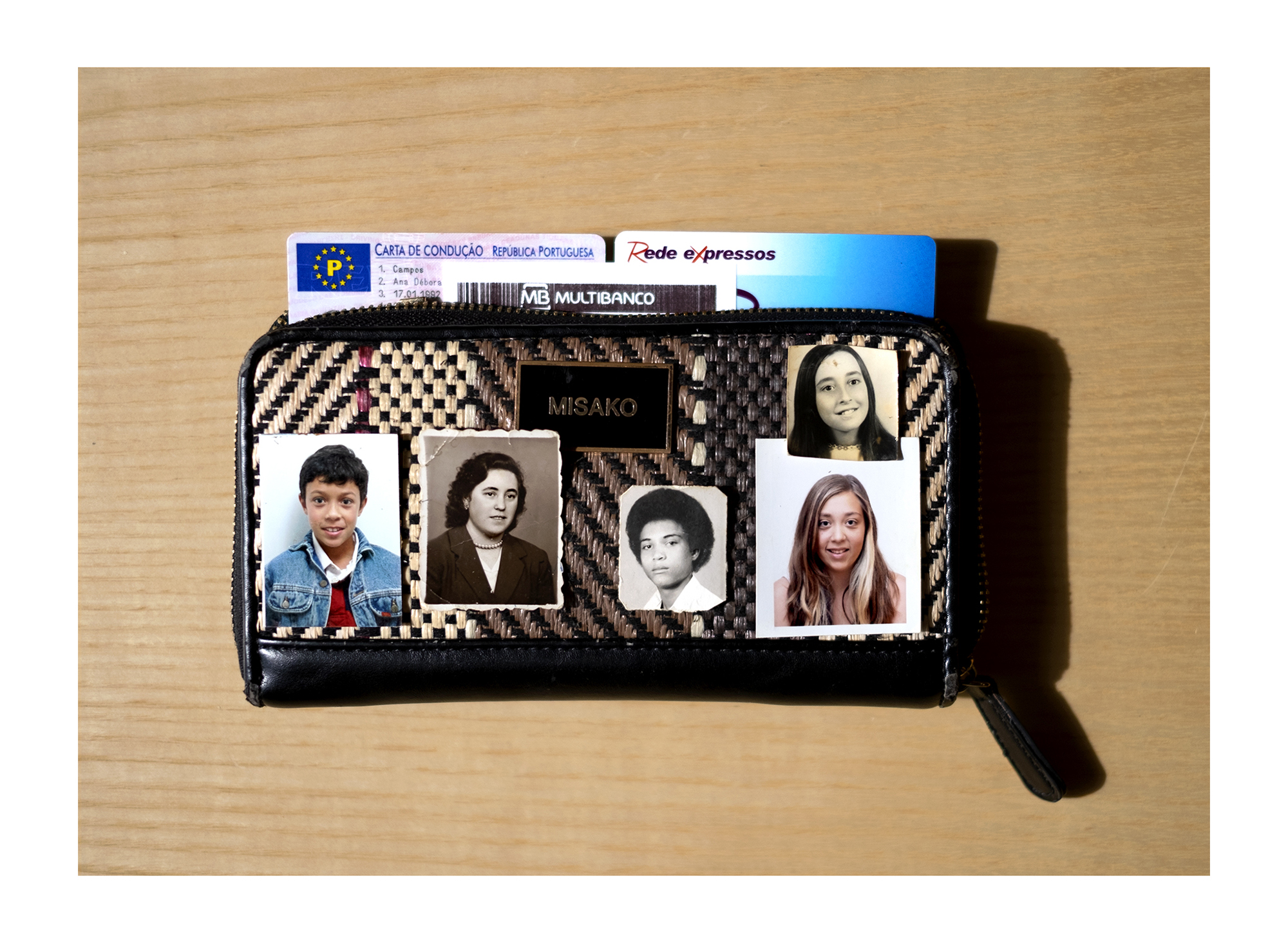 Carteira castanha com fotografias tipo passe e uma figura religiosa.