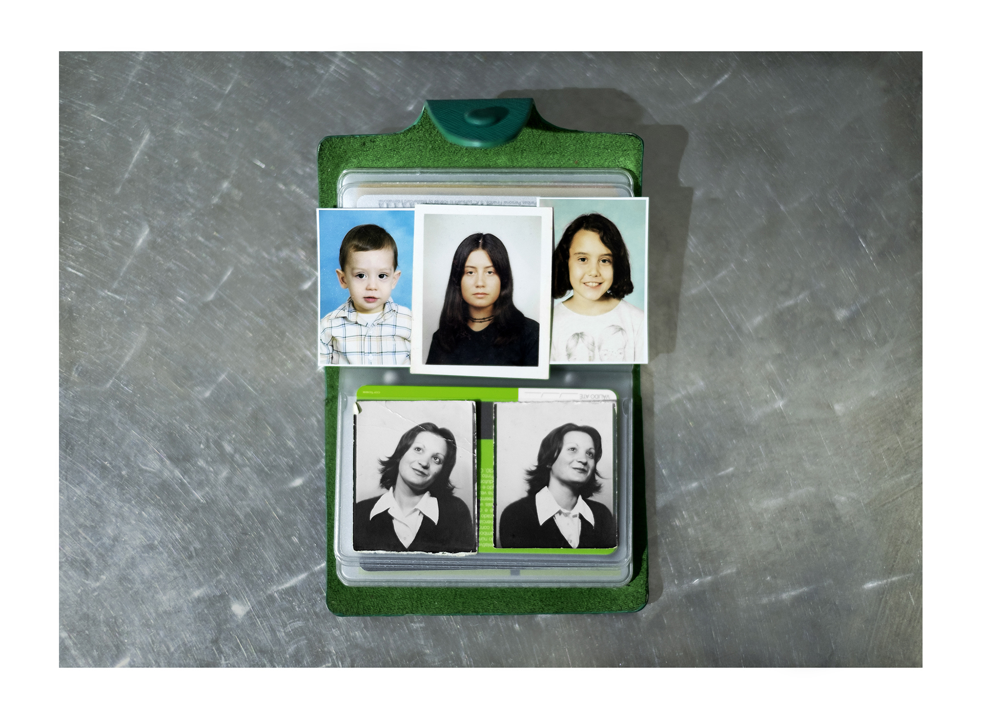 Carteira verde com uma fotografia tipo passe a preto e branco e um cartão religioso.