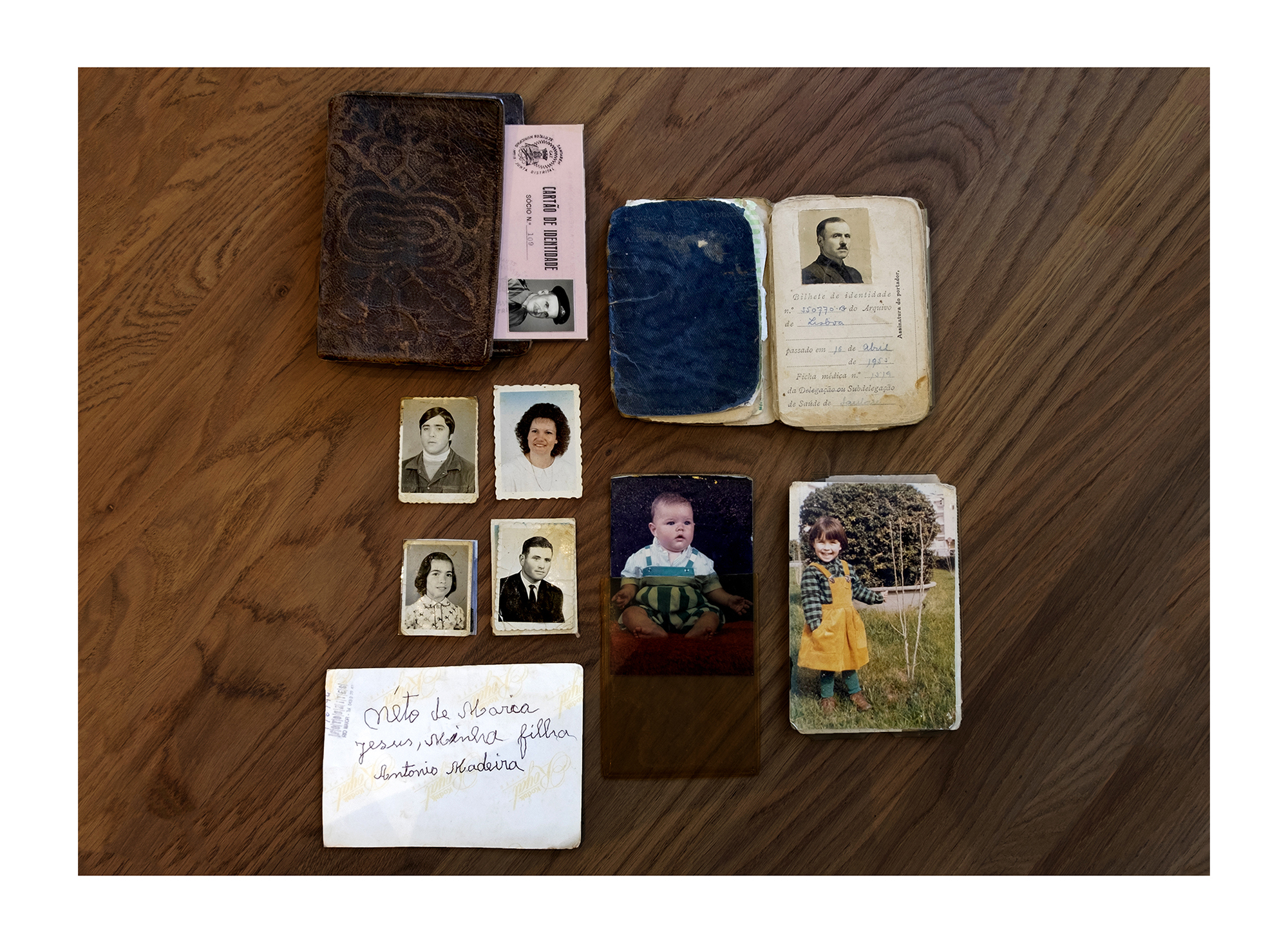 Carteira castanha com duas fotografias tipo passe e flores secas no meio.