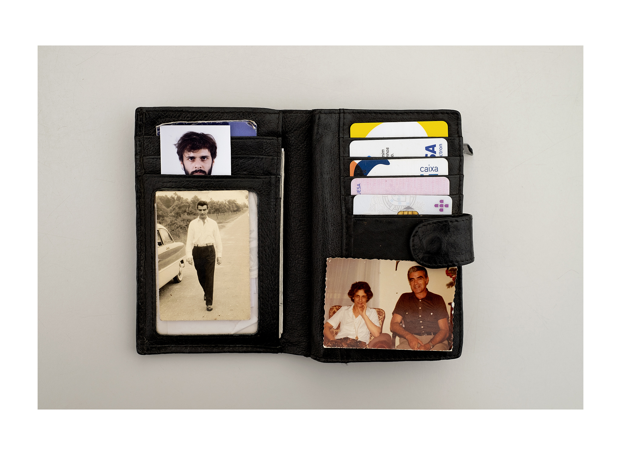 Carteira castanha com fotografia tipo passe a preto branco com uma moldura dourada.