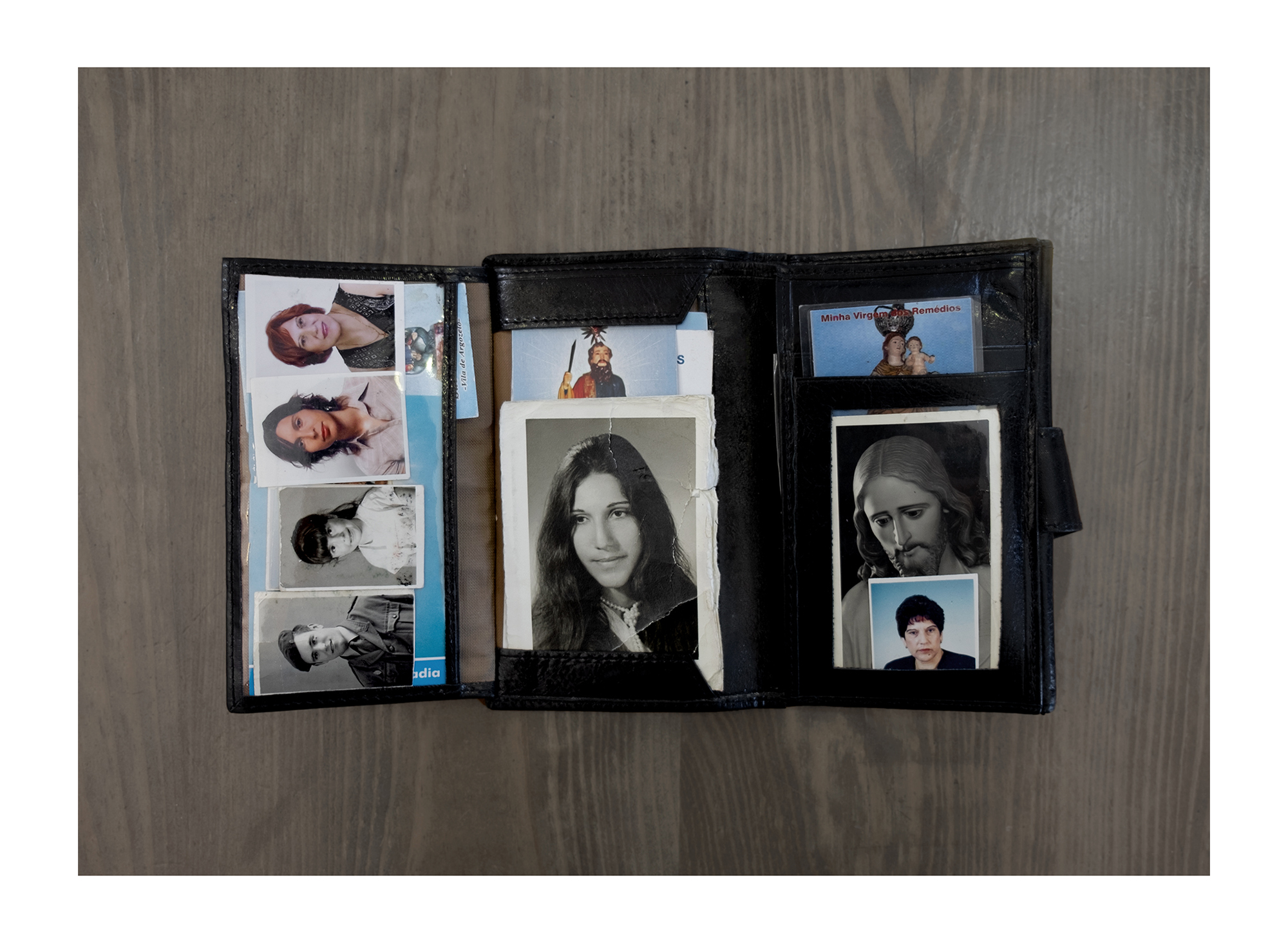 Objetos dispersos em mesa: fotografias tipo passe e documentos de identificação.